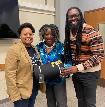Three DEI members holding PFW blanket from Ripples program.